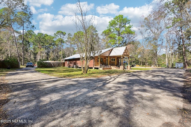 log home featuring covered porch and a front yard