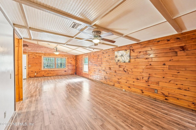 unfurnished living room with vaulted ceiling with beams, wood walls, ceiling fan, and light wood-type flooring