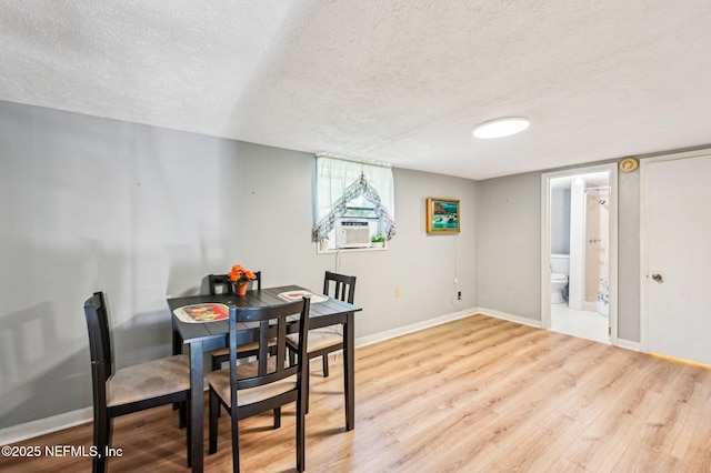 dining room with cooling unit, a textured ceiling, and light wood-type flooring