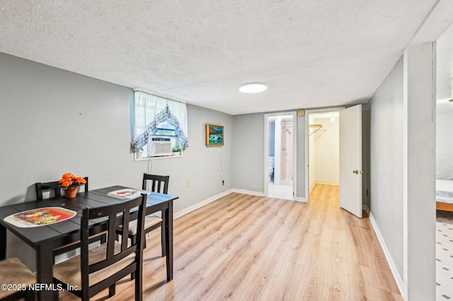 dining room with cooling unit, a textured ceiling, and light hardwood / wood-style floors