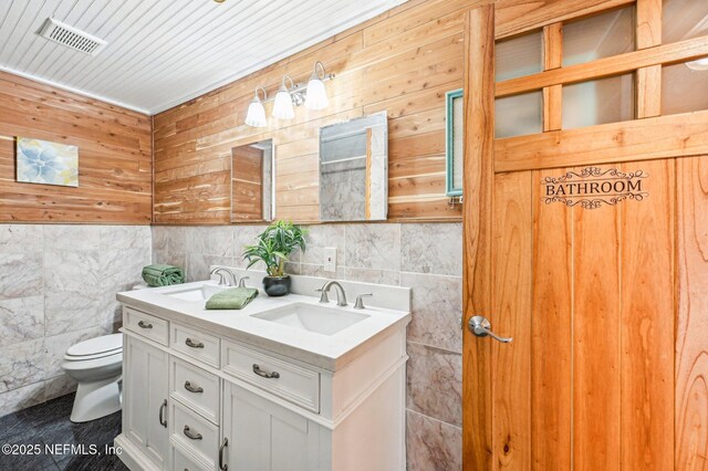 bathroom featuring vanity, tile walls, and toilet