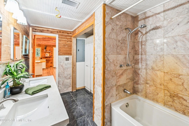 bathroom with tiled shower / bath, vanity, electric panel, and wood walls