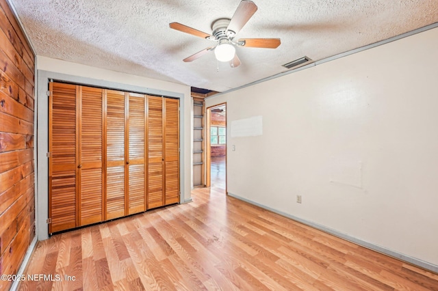 unfurnished bedroom with ceiling fan, light hardwood / wood-style flooring, a closet, and a textured ceiling