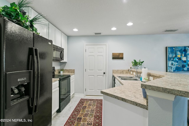 kitchen featuring black appliances, white cabinetry, and sink