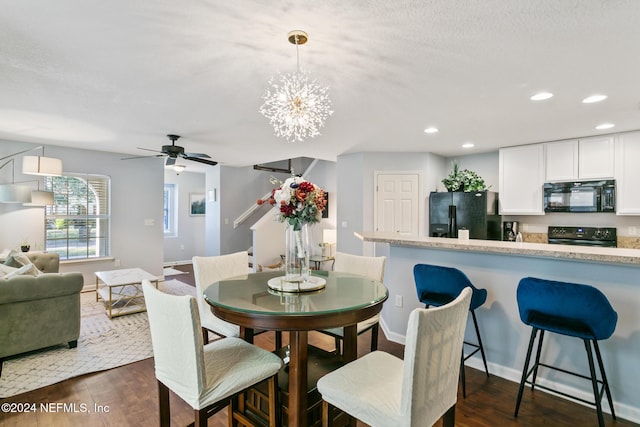 dining room featuring a textured ceiling, ceiling fan with notable chandelier, and dark wood-type flooring