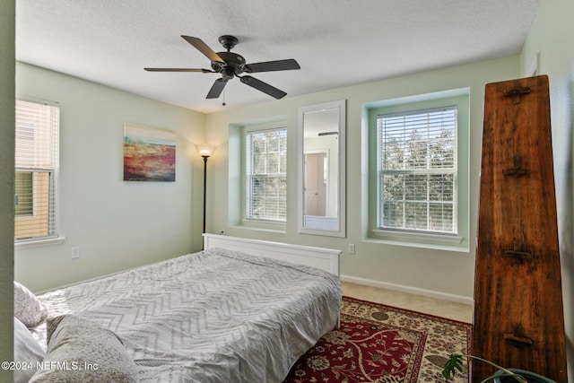 carpeted bedroom featuring ceiling fan and a textured ceiling