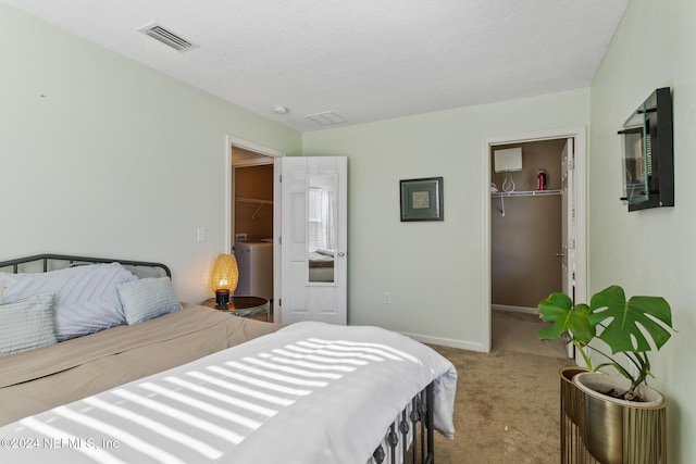 bedroom featuring light carpet, a textured ceiling, a spacious closet, and a closet