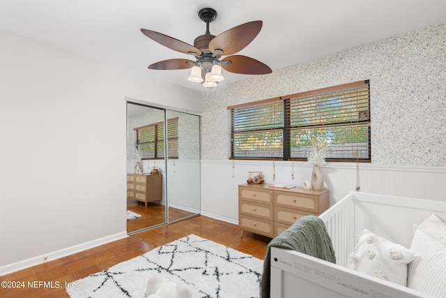 bedroom featuring ceiling fan, a closet, and parquet floors