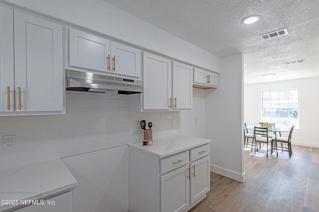 kitchen featuring white cabinets and light stone counters