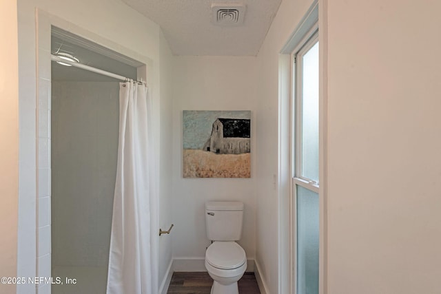 bathroom featuring hardwood / wood-style floors, toilet, a textured ceiling, and a shower with shower curtain