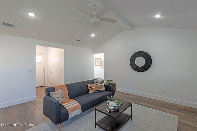 living room featuring lofted ceiling with beams, ceiling fan, light wood-type flooring, and a textured ceiling