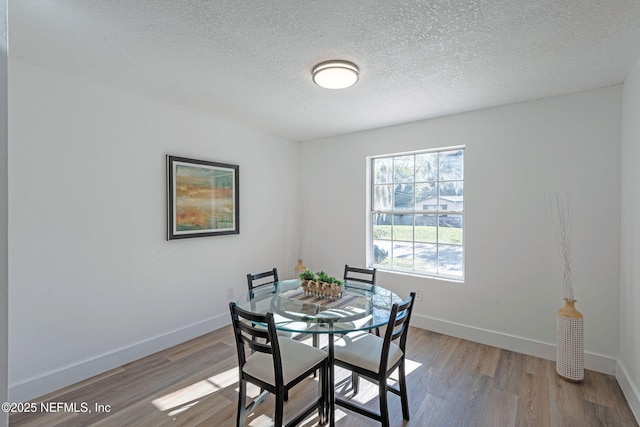 dining room with a textured ceiling and light hardwood / wood-style floors