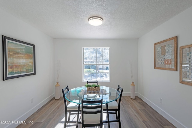 dining area featuring wood-type flooring and a textured ceiling