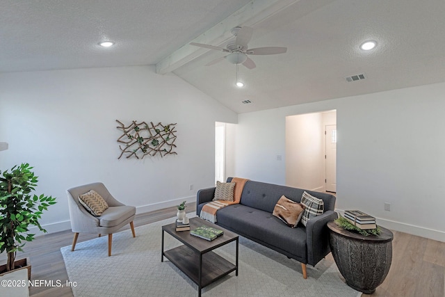 living room featuring ceiling fan, light hardwood / wood-style flooring, lofted ceiling with beams, and a textured ceiling