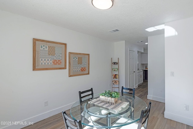 dining space with light hardwood / wood-style floors and a textured ceiling