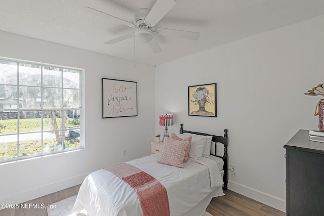 bedroom with hardwood / wood-style flooring, ceiling fan, and a textured ceiling