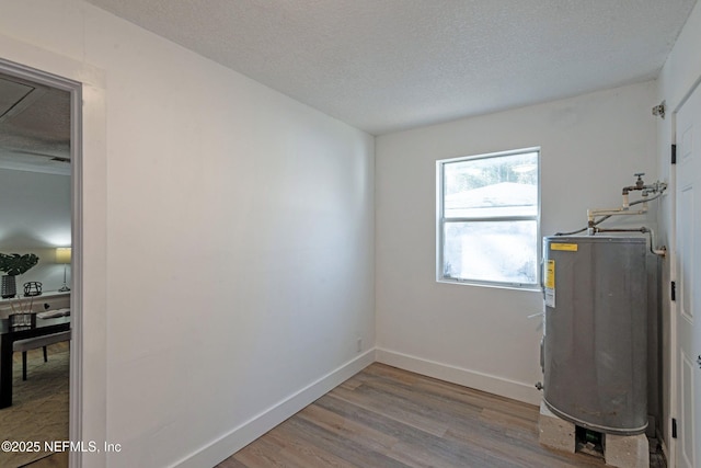 clothes washing area with hardwood / wood-style floors, a textured ceiling, and water heater