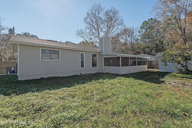 rear view of house featuring a lawn and a sunroom