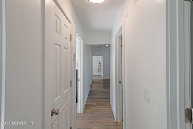 hall featuring a textured ceiling and light wood-type flooring