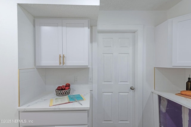 kitchen featuring white cabinetry, decorative backsplash, and light stone countertops