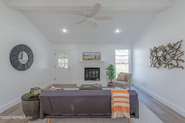 living room with hardwood / wood-style floors, vaulted ceiling with beams, a large fireplace, and a wealth of natural light