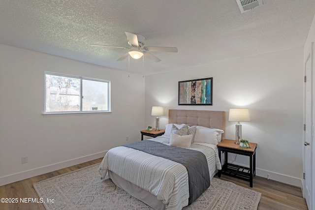 bedroom with ceiling fan, hardwood / wood-style floors, and a textured ceiling