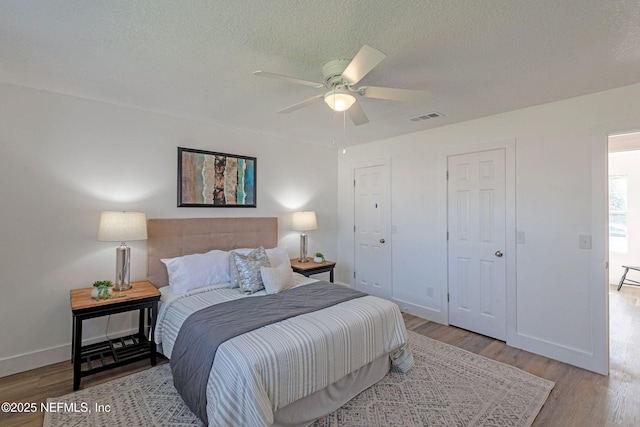 bedroom featuring ceiling fan, light hardwood / wood-style flooring, and a textured ceiling