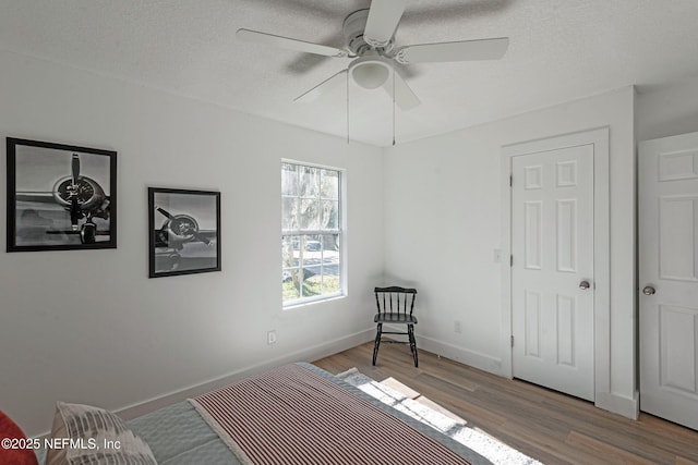 bedroom with ceiling fan, wood-type flooring, and a textured ceiling