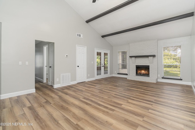 unfurnished living room featuring beam ceiling, ceiling fan, a brick fireplace, high vaulted ceiling, and light hardwood / wood-style floors