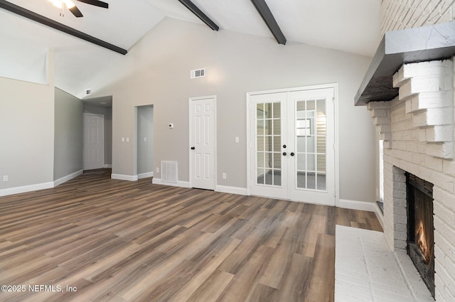 unfurnished living room featuring beam ceiling, ceiling fan, french doors, a brick fireplace, and wood-type flooring