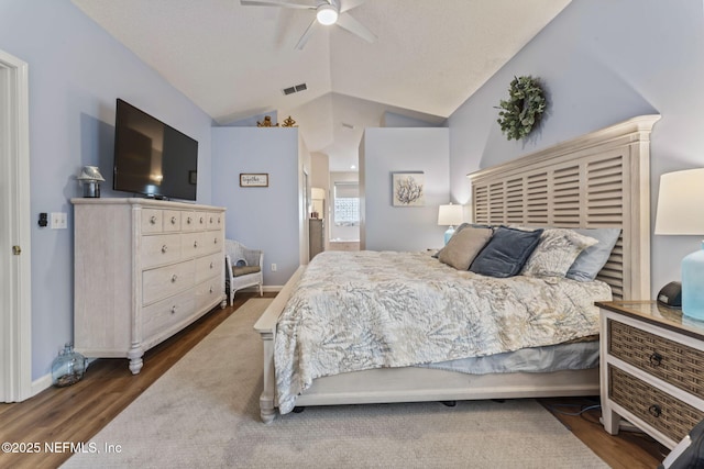 bedroom featuring dark hardwood / wood-style flooring, ceiling fan, lofted ceiling, and connected bathroom