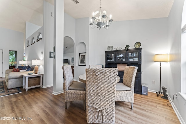 dining area with hardwood / wood-style floors, high vaulted ceiling, and a chandelier