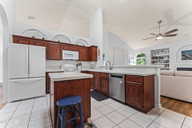 kitchen featuring built in features, a kitchen island, white appliances, and light tile patterned floors