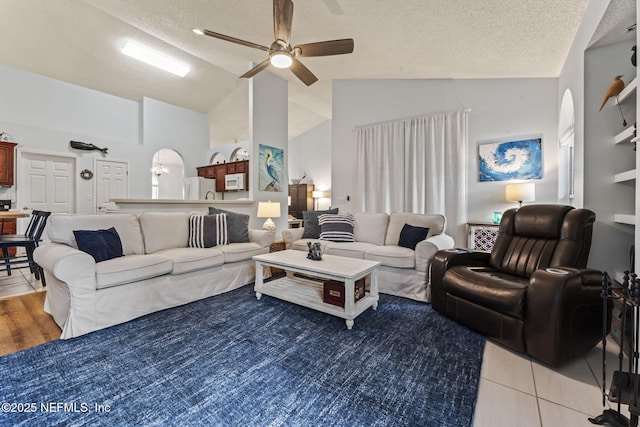 living room featuring a textured ceiling, ceiling fan, tile patterned floors, and lofted ceiling