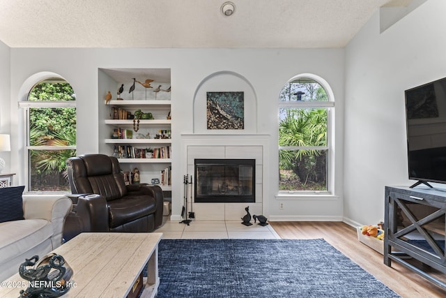 living room featuring a fireplace, light wood-type flooring, a textured ceiling, and plenty of natural light