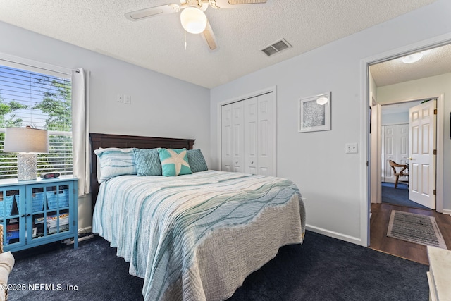 carpeted bedroom with ceiling fan, a closet, and a textured ceiling