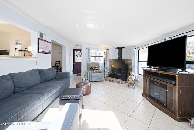 living room with a wood stove, crown molding, and light tile patterned flooring