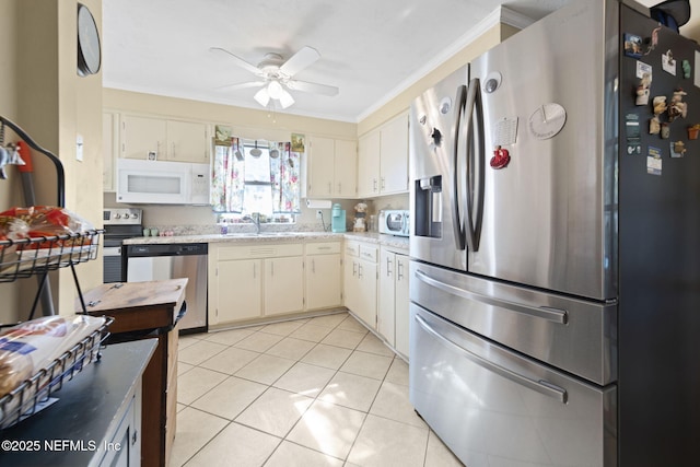 kitchen featuring sink, crown molding, ceiling fan, light tile patterned floors, and appliances with stainless steel finishes