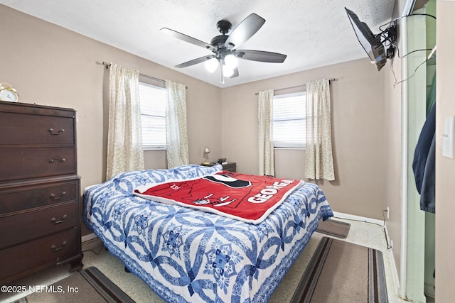 carpeted bedroom featuring ceiling fan, a textured ceiling, and multiple windows