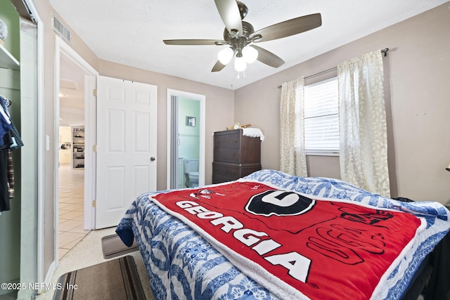 tiled bedroom featuring ensuite bath and ceiling fan