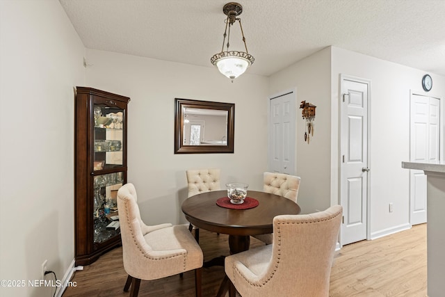 dining space with a textured ceiling and light hardwood / wood-style floors