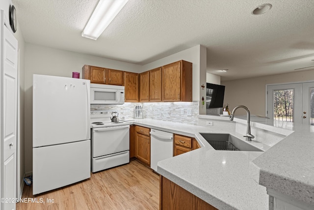 kitchen with kitchen peninsula, decorative backsplash, white appliances, and sink