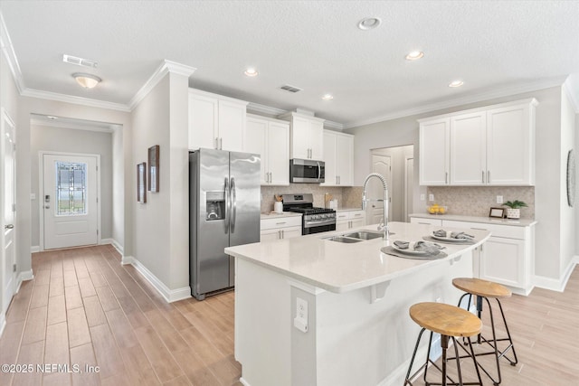 kitchen featuring white cabinets, sink, an island with sink, and stainless steel appliances