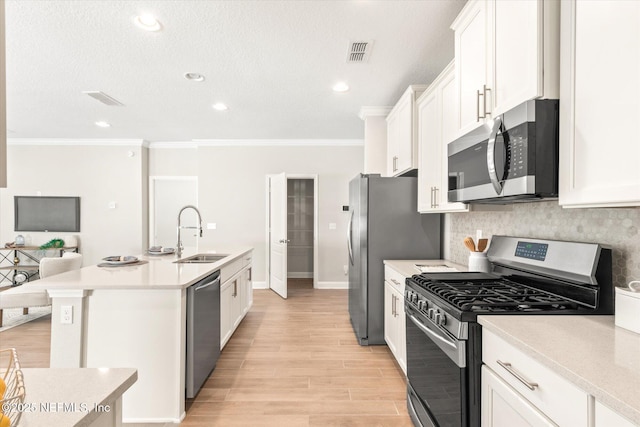 kitchen featuring white cabinets, sink, ornamental molding, an island with sink, and stainless steel appliances