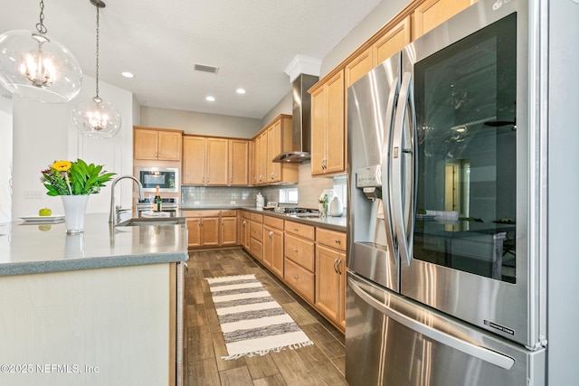 kitchen with wall chimney range hood, pendant lighting, decorative backsplash, stainless steel appliances, and light brown cabinetry