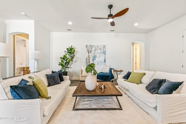 living room with a textured ceiling and ceiling fan