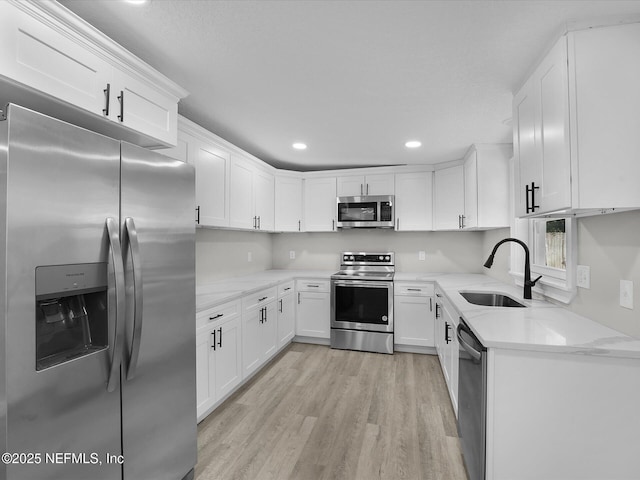 kitchen featuring light stone counters, stainless steel appliances, white cabinetry, and sink