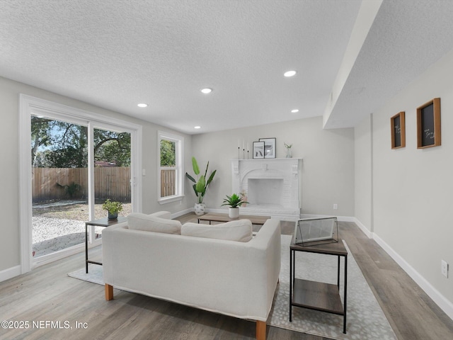 living room with a brick fireplace, hardwood / wood-style flooring, and a textured ceiling