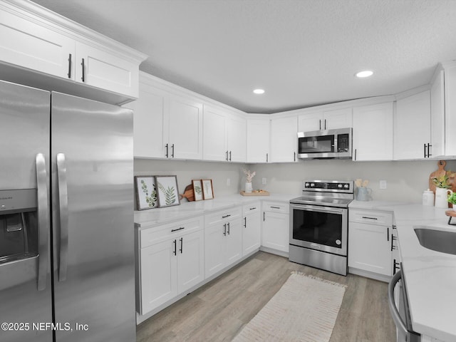 kitchen featuring white cabinetry, stainless steel appliances, and light stone counters