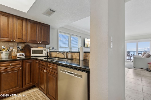 kitchen with stainless steel dishwasher, light tile patterned flooring, a healthy amount of sunlight, and sink